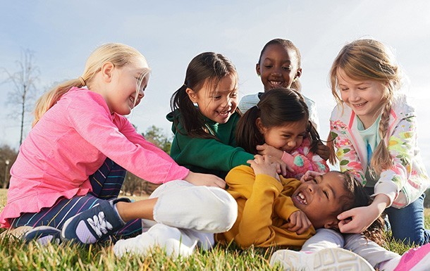 GroupofGirls_group-of-daisy-brownie-elementary-school-girl-scouts-playing-outside-grass-smiling-tickling-sunshine_610x385