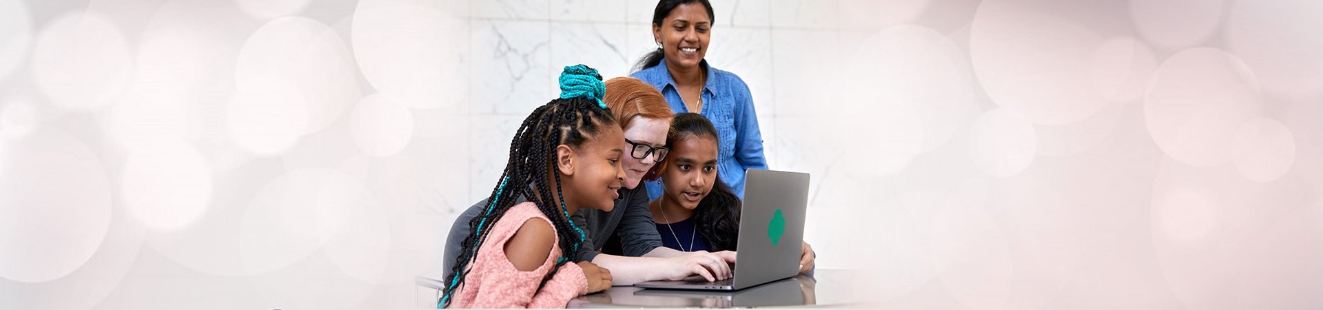  group of girl scouts looking at laptop computer with adult volunteer 
